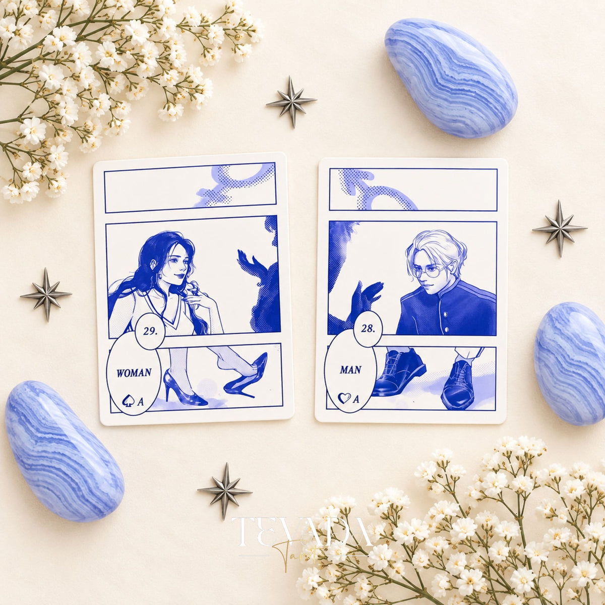 Hands hold open the bilingual Blues Lenormand guidebook, with printed card explanations beside blue stones and white flowers.