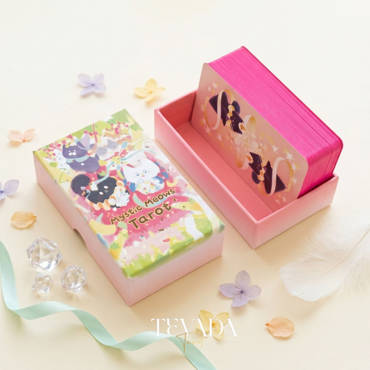 ミスティック ニャーズ タロット ピンク デラックス デッキは、プレミアム 330gsm ブラック コア カードに夢のような猫のイラストが描かれ、青いスプラッターとシルバーの輝きエッジが特徴で、磁気フリップトップの硬質ボックスに入っています。