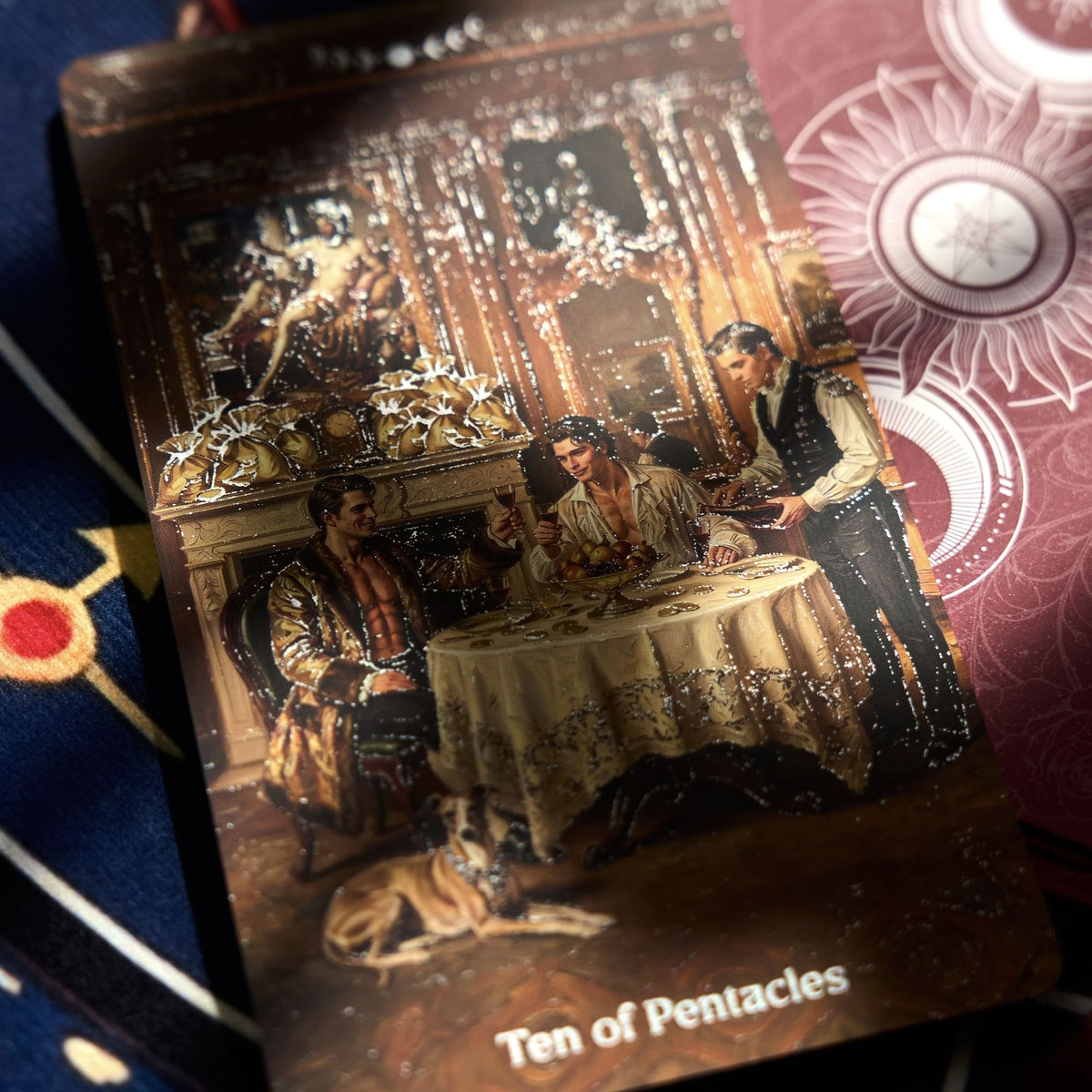 Close-up Pact of the Arcana Tarot card showing an ornate mythic banquet scene with reflective silver foil