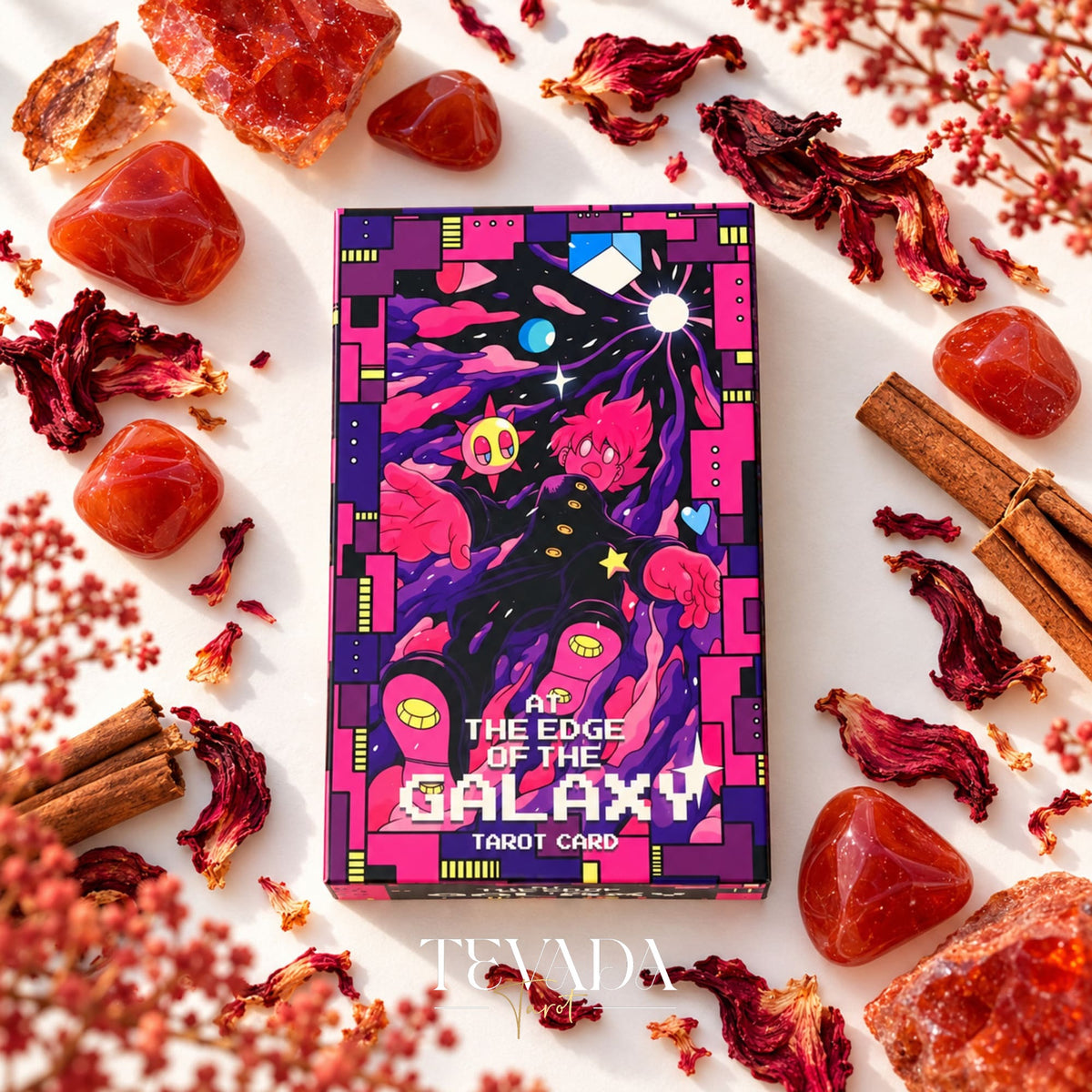 At the Edge of the Galaxy Tarot purple and pink illustrated box displayed among red flowers, crystals and cinnamon sticks.