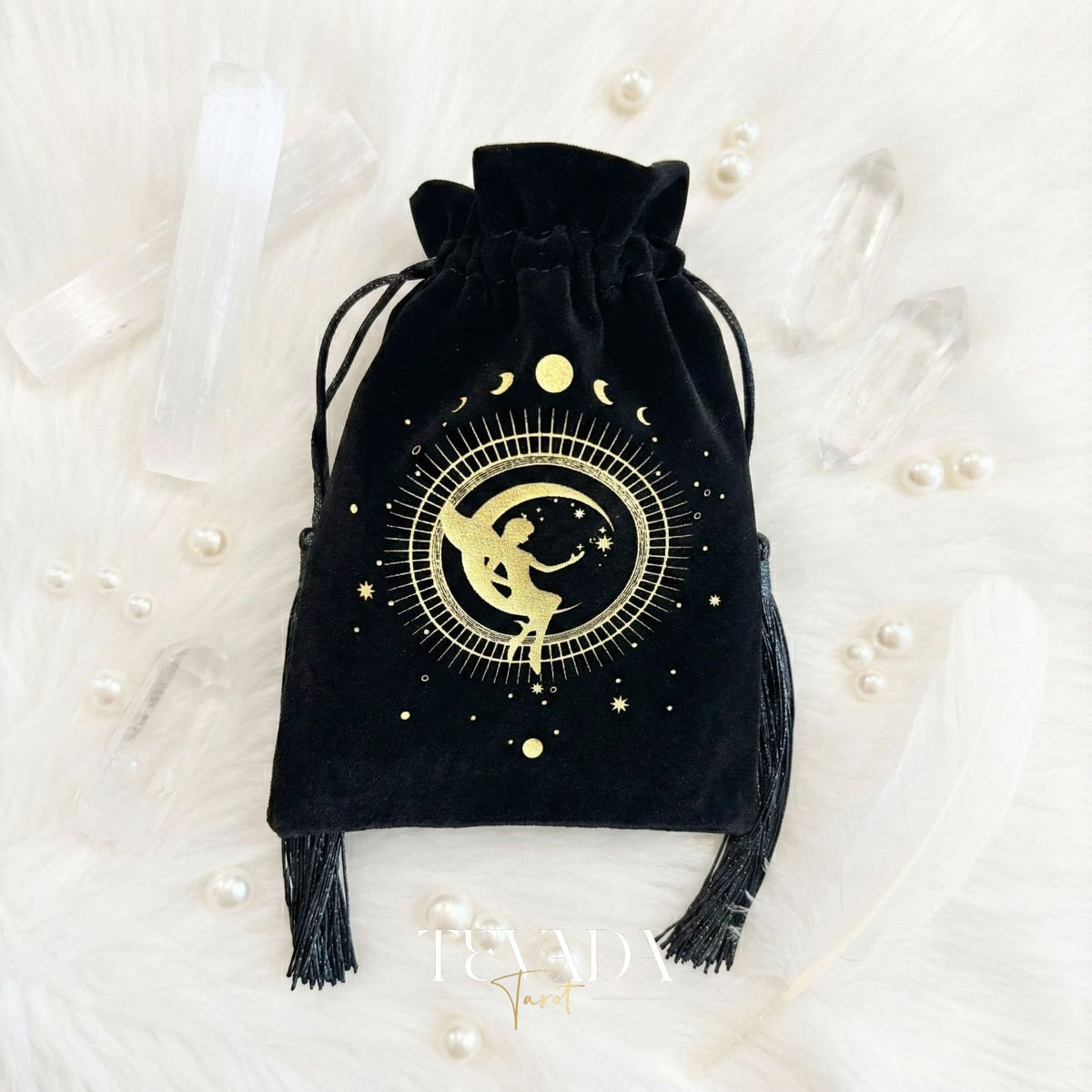 Bolsa de tarot de terciopelo negro con estampado dorado y borlas para proteger barajas de tarot y cristales en un altar de brujas.