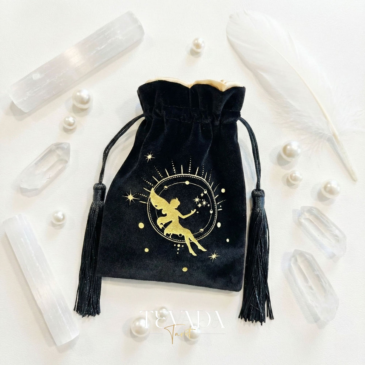 Bolsa de tarot de terciopelo negro con estampado dorado y borlas para proteger barajas de tarot y cristales en un altar de brujas.