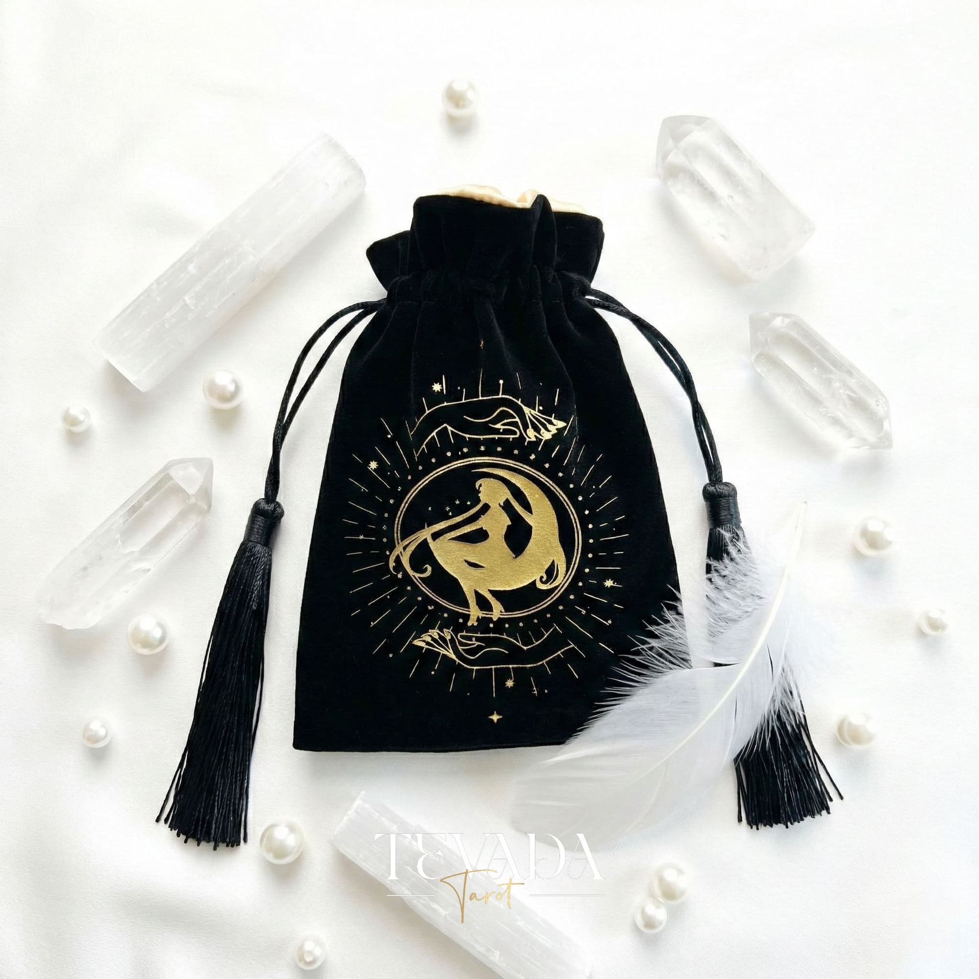 Bolsa de tarot de terciopelo negro con estampado dorado y borlas para proteger barajas de tarot y cristales en un altar de brujas.