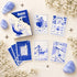The Blues Lenormand box and a spread of Klein-blue comic-style cards with everyday symbols on a pale floral background.