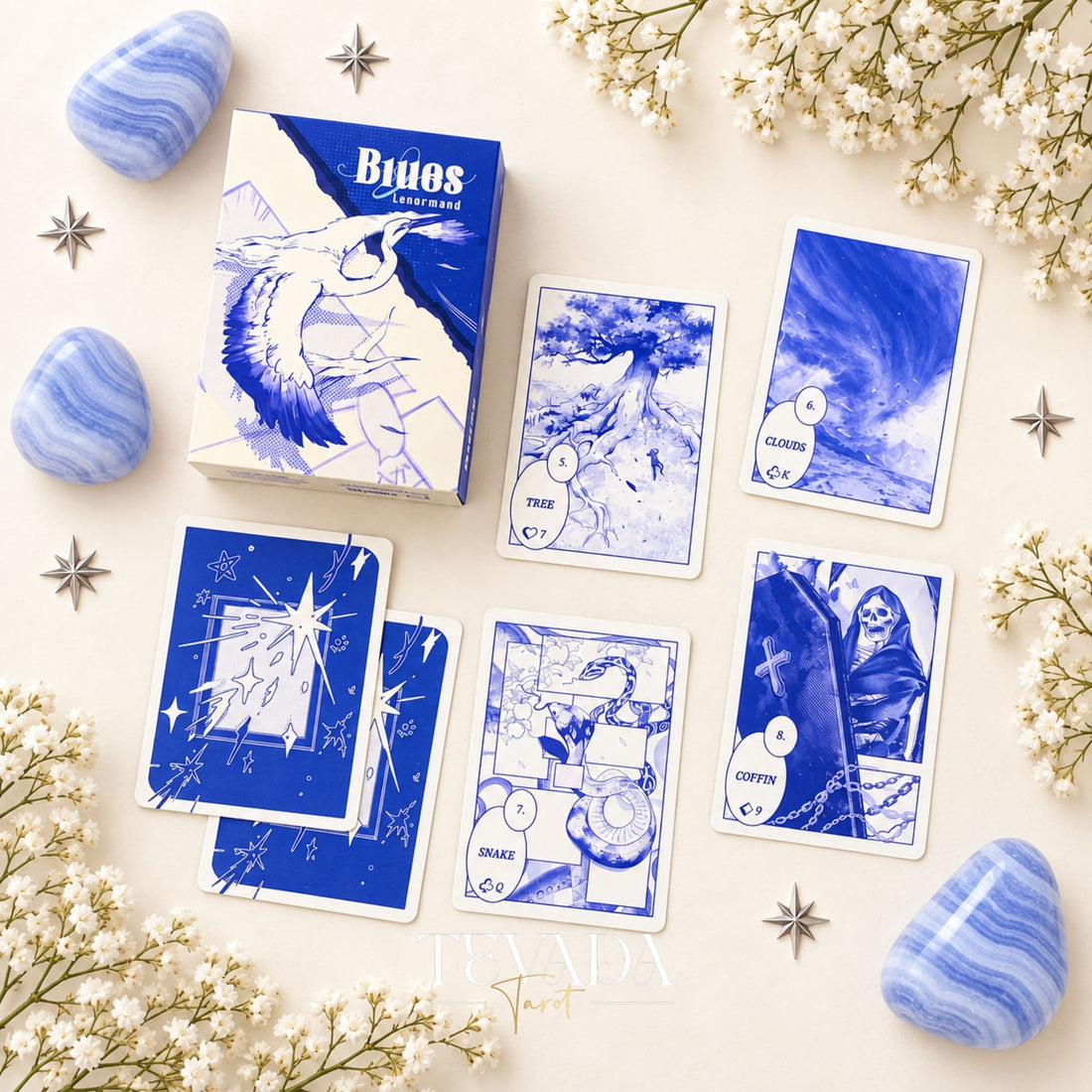 The open Blues Lenormand deck box and blue card case displayed with blue agate stones and white flowering branches.