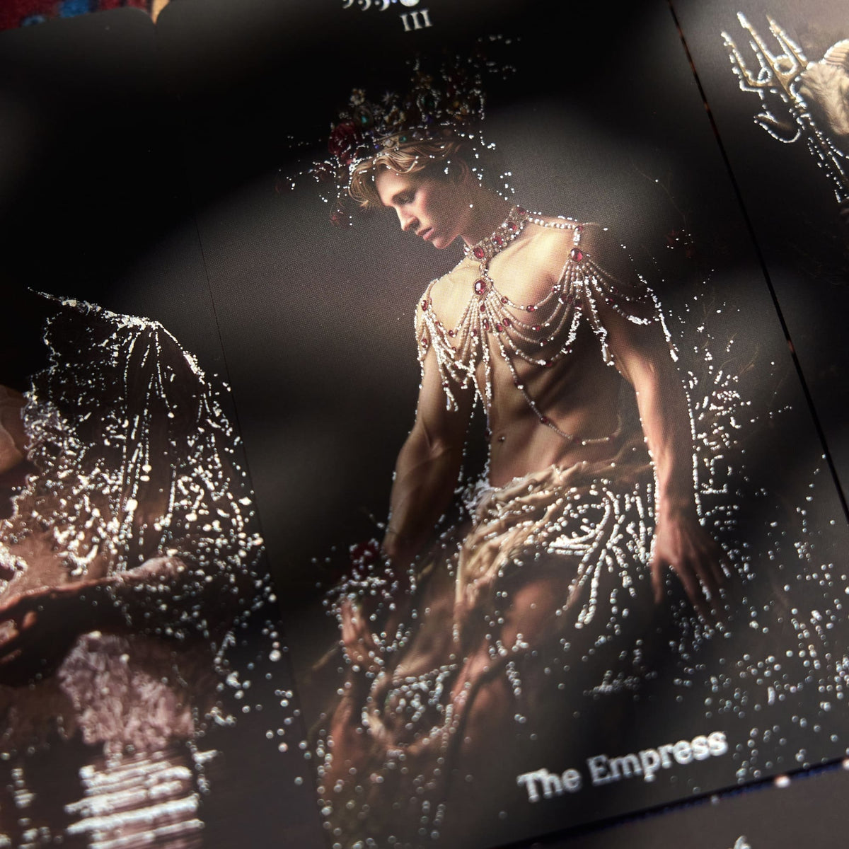 Close-up Pact of the Arcana Tarot card featuring a contemplative male figure with bright silver foil accents