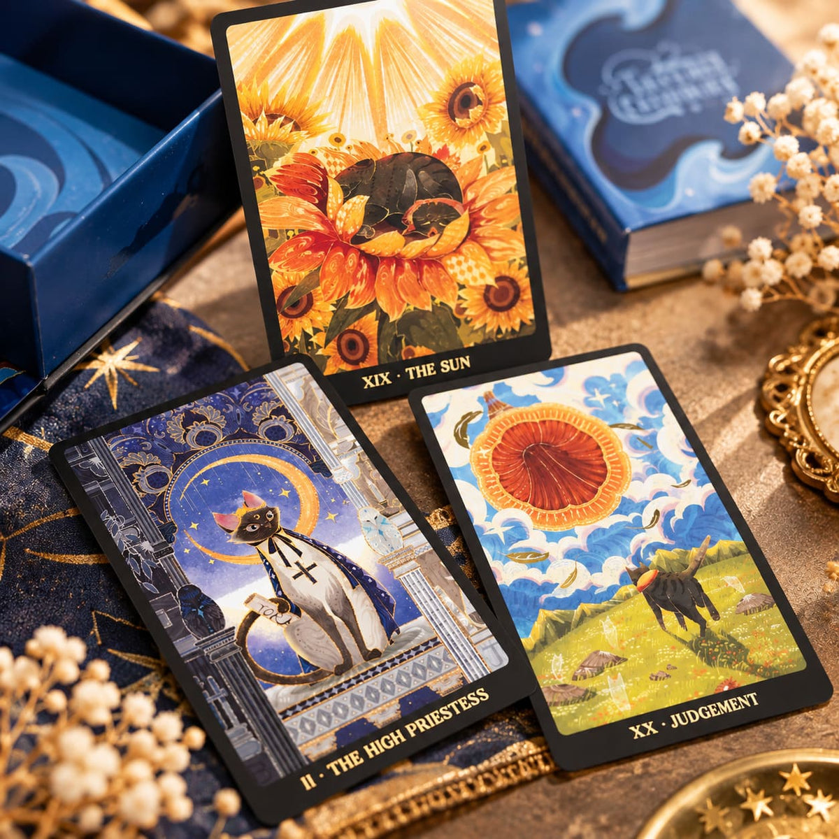 Tales of Catrealm Tarot DELUXE Edition The Sun, The High Priestess and Judgment cards beside the blue box.