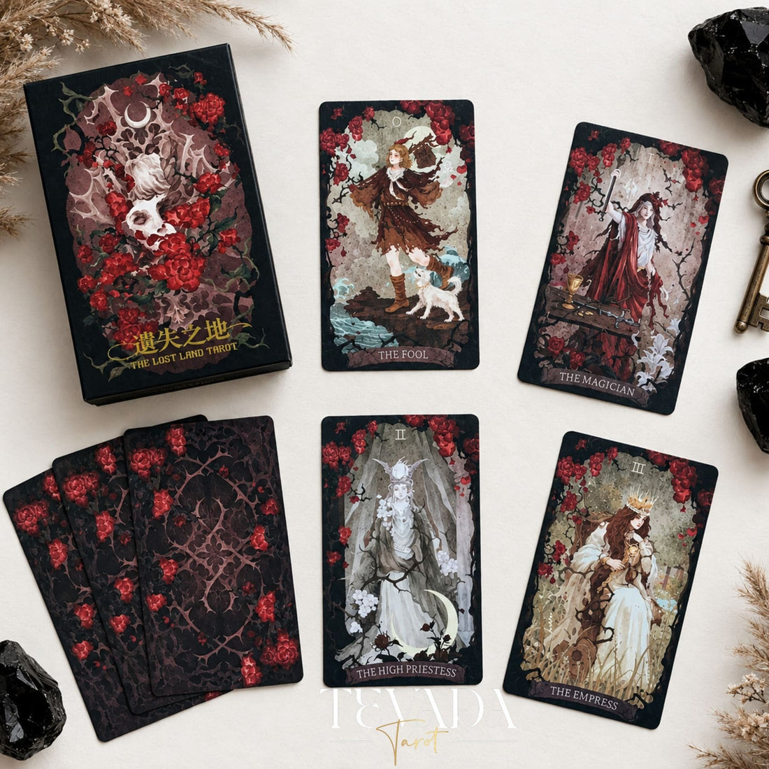 The Lost Land Tarot Fading Edition deck box and dark watercolor tarot cards arranged with black crystals and a vintage key